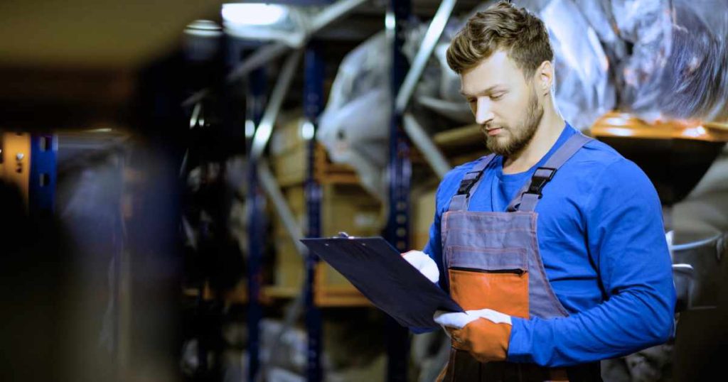 automotive worker with a clipboard checking inventory manually.